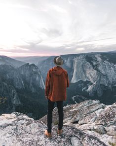 a person standing on top of a mountain looking out at the valley and mountains in the distance