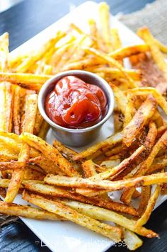 french fries on a plate with ketchup in a small bowl next to them