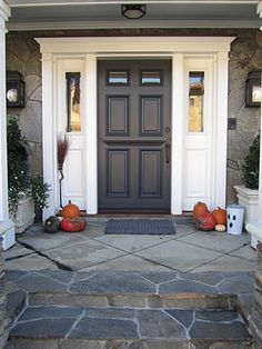 the front entrance to a house with stone steps and pumpkins on either side of the door