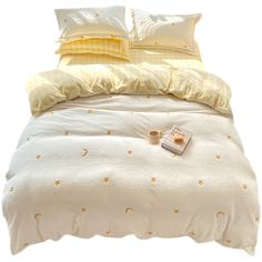 a bed with yellow and white comforters, pillows and blankets on top of it