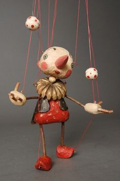 a figurine is hanging from strings on a gray background with red and white polka dots