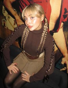 a woman with blonde hair and braids posing for the camera