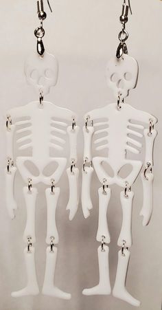 Hand-crafted Pierced Earrings Unique and One-of-a-Kind Skeleton Earrings Approximately 3-3/4" long x 1-1/8" wide Featuring resin skeleton bones, hand-assembled with stainless jumping. They are lightweight and elegant and are set with high quality, stainless, hypoallergenic, ear wires. Carded. Made in a clean, smoke free, pet free and temperature controlled studio. Ready to ship immediately. Halloween Skull Jewelry In Bone Color, Halloween Skull Shaped Bone Jewelry, White Gothic Handmade Earrings, Handmade White Gothic Earrings, White Skull Jewelry For Day Of The Dead, White Skull-shaped Halloween Jewelry, Halloween Skull Jewelry In White, White Skull Jewelry For Halloween, Halloween White Skull Jewelry