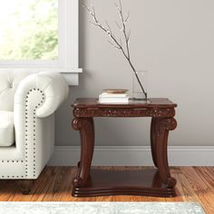 a living room with a white couch and chair next to a table that has a vase on it