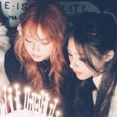 two girls looking at a birthday cake with candles