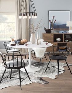 a dining room table with chairs and a rug on the floor in front of it