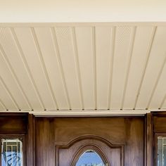 a wooden front door with two sidelights and a round mirror on the outside wall