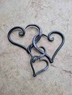 two metal heart shaped hooks sitting on top of a cement floor