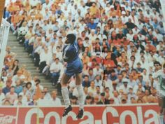 a soccer player is jumping up in the air to catch a ball while people watch from the stands