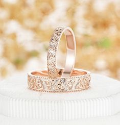 two wedding rings are sitting on top of a white cushioned surface in front of a blurry background