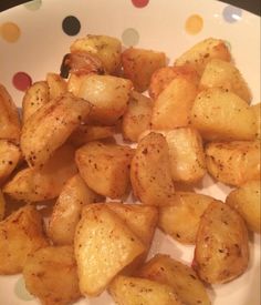 a white plate topped with cooked potatoes on top of a polka dot covered tablecloth