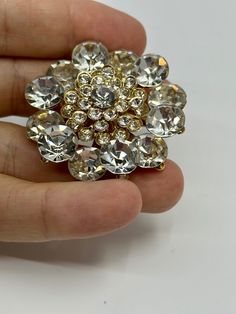 Add some sparkle to any occasion with this vintage Flower Cluster Rhinestone Clear Brooch Pin. The stunning round Rhinestone gems are set in an elegant cluster shape, making it the perfect accessory for weddings, anniversaries, birthdays, and more. The pin's intricate flower design adds a touch of charm, making it a great gift for Mother's Day, Christmas, graduation, or Valentine's Day. This Brooch Pin is a one-of-a-kind piece, handcrafted with care and attention to detail. Its vintage style adds a touch of nostalgia, making it a timeless addition to any jewelry collection. Whether you're dressing up or adding some flair to your everyday look, this stunning piece is sure to turn heads. Flower Cluster Silver Rhinestone Clear Brooch Pin Vintage Materials: silver tone metal & rhinestones Cond Elegant Round Rhinestone Brooches, Elegant Round Brooches With Rhinestones, Round Rhinestone Brooches For Formal Occasions, Formal Round Rhinestone Brooches, Formal Round Brooches With Rhinestones, Round Formal Brooches With Rhinestones, Gold Wedding Brooch, Gold Round Brooches For Wedding, Gold Crystal Jeweled Brooches