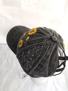 a gray hat with sunflowers on it sitting on top of a white table