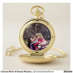 a gold pocket watch with an image of two children on the front, and a chain attached to it