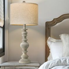 a white lamp sitting on top of a table next to a bed