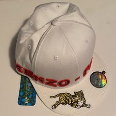 Brand New With Tags Kenzo X H&M Baseball Cap. Never Been Worn. Limited Edition Part Of The Sold Out Collaboration. According To The Tag This Is A Size Large. Designer White Visor Baseball Cap, Designer Baseball Cap For Streetwear, Designer White Snapback Hat, Designer Streetwear Cap, Designer White Flat Brim Hat, Designer White Visor Hat, Designer Visor Hats For Spring, Designer White Hat With Curved Brim, Designer White Hats For Spring