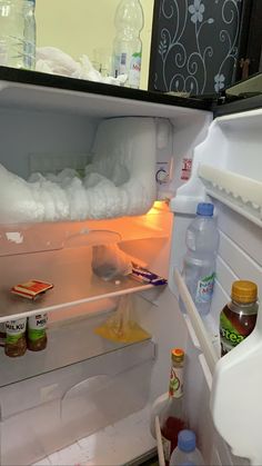 an open refrigerator filled with lots of ice and water next to other items on the shelves