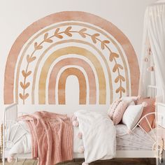 a white bed with pink and gold decor on the headboard next to a rainbow wall mural