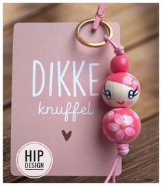 a pink keychain with a cute doll hanging from it's side and the words dikke knuffel on it