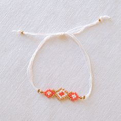 the beaded bracelet is made with red beads and gold accents on a white background