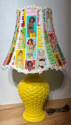 a yellow table lamp with pictures of women on it and a cordless charger next to it