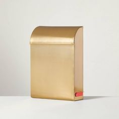 a gold mailbox sitting on top of a white table next to a red object