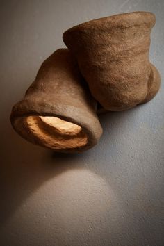 two pieces of clay sitting on top of a white wall next to a light bulb