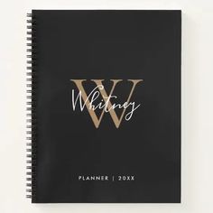 a spiral notebook with the word w in gold foil on it and black paper underneath