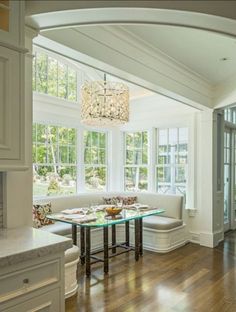 a living room filled with furniture and a chandelier hanging from the ceiling over a wooden floor