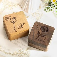 two personalized wooden coasters sitting on top of a white table with flowers in the background