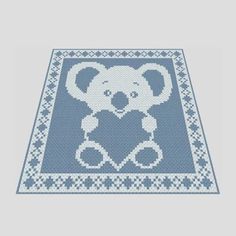 a blue and white knitted rug with a koala bear holding a heart on it