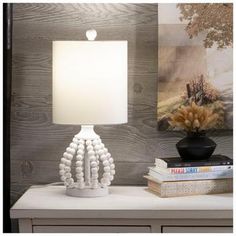 a white lamp sitting on top of a table next to a book and some pictures