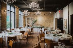 a room filled with lots of tables covered in white tablecloths and centerpieces