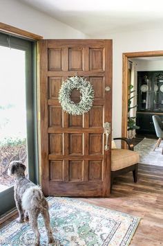 a dog standing in front of a door with a wreath on it's side