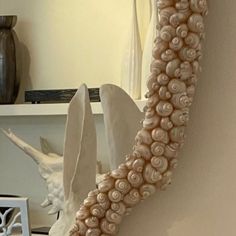 a mirror that has shells on it in the shape of a wave and is next to a shelf with vases