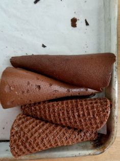 three cones of chocolate ice cream in a tray on a table with other food items