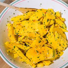 a white bowl filled with yellow food on top of a wooden table