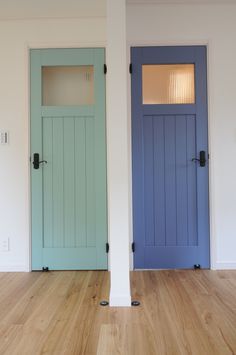 an empty room with two blue doors and wood flooring on either side of the door