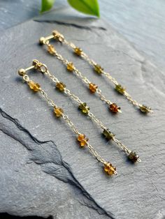 These stunning faceted tourmaline gemstone dangles are truly one-of-a-kind! The earrings feature warm, rich yellows and browns on the front, while the back reveals a fun pop of vibrant greens. Each stone is carefully wire-wrapped onto a delicate 14k gold-filled chain, keeping them lightweight and super comfy for all-day wear! EARRING FEATURES Total Length: 2.5 inches Metal: 14k Gold Filled Gemstone: 2mm Faceted Tourmaline  ♥ ABOUT 14K GOLD FILLED JEWELRY Gold-filled components contain 100+ times more real gold than gold-plated components and are very durable and tarnish-resistant. Gold-filled jewelry is a beautiful, affordable alternative to solid gold, and can be worn by people with sensitive skin. ♥ All orders come beautifully hand-packaged with care, making it the perfect gift for yours Tourmaline Earrings, Boho Fall, Earrings Long, Tourmaline Gemstone, Gold Filled Jewelry, Jewelry Gold, Boho Earrings, Gemstone Colors, Gemstone Earrings