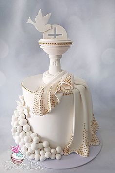 a white cake decorated with pearls and a cross