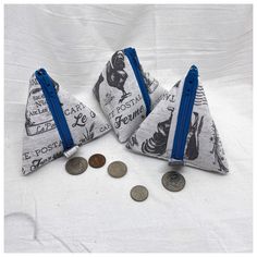 three zippered coin purses sitting on top of a white cloth covered tablecloth