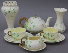 four pieces of porcelain tea set with green leaves on the rims and saucers