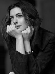 a black and white photo of a woman with her hand on her chin looking at the camera