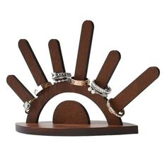 a wooden stand with rings and bracelets on it's sides in front of a white background