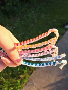 a hand holding several different colored hair ties