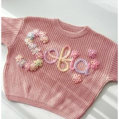 a pink sweater with flowers on it and the word hope written in crochet