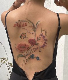 the back of a woman's neck with flowers and butterflies tattooed on her lower back