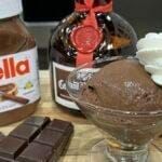 chocolate ice cream in a glass bowl next to two bottles of gelato and some candy