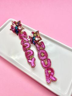 "The Sparkly Pink Happy Hour Beaded Earrings are the ultimate accessory for celebrating birthdays, TGIF moments, and unforgettable girls' nights. These dazzling earrings are meticulously crafted with intricate beadwork, showcasing the letters that spell out \"Happy Hour\" in a vibrant and glamorous design. These sparkling beauties will add a touch of glamor and excitement to your Happy Hour outfit! Not only are these earrings visually captivating, but they are also lightweight and comfortable to Pink Earrings For Valentine's Day Celebration, Pink Fun Jewelry For Party, Pink Fun Party Jewelry, Fun Pink Party Jewelry, Cute Party Earrings For Mother's Day, Cute Earrings For Mother's Day Party, Playful Pink Earrings For Party, Cute Beaded Jewelry For Party, Playful Pink Jewelry For Party