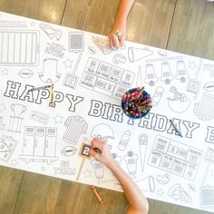 two children are drawing on a happy birthday sign with crayons and colored pencils